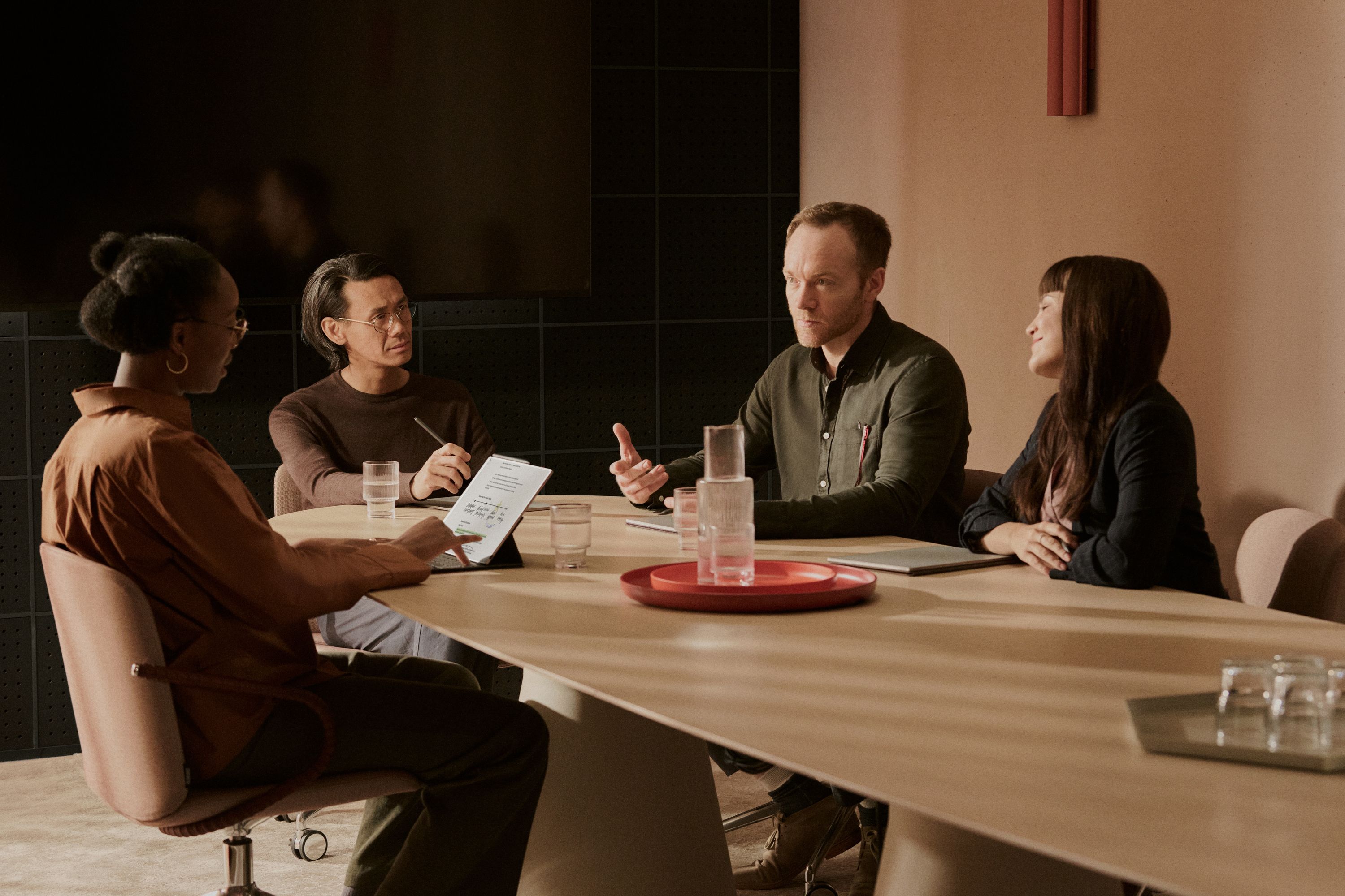 Four people sitting at conference table conducting a meeting and note taking with reMarkable tablets