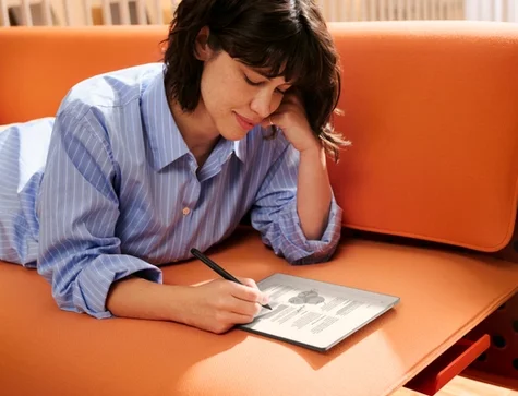 A woman on a sofa working on highlighting a document on reMarkable Paper Pure