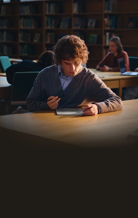 A male student sitting at his desk, working focused on his reMarkable Paper Pro paper tablet.
