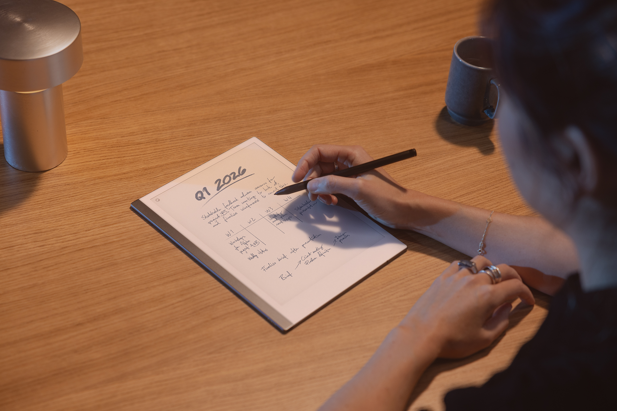 A reMarkable paper tablet with handwritten notes and person writing with the Marker.
