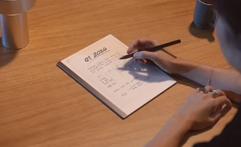 A reMarkable paper tablet with handwritten notes and person writing with the Marker.