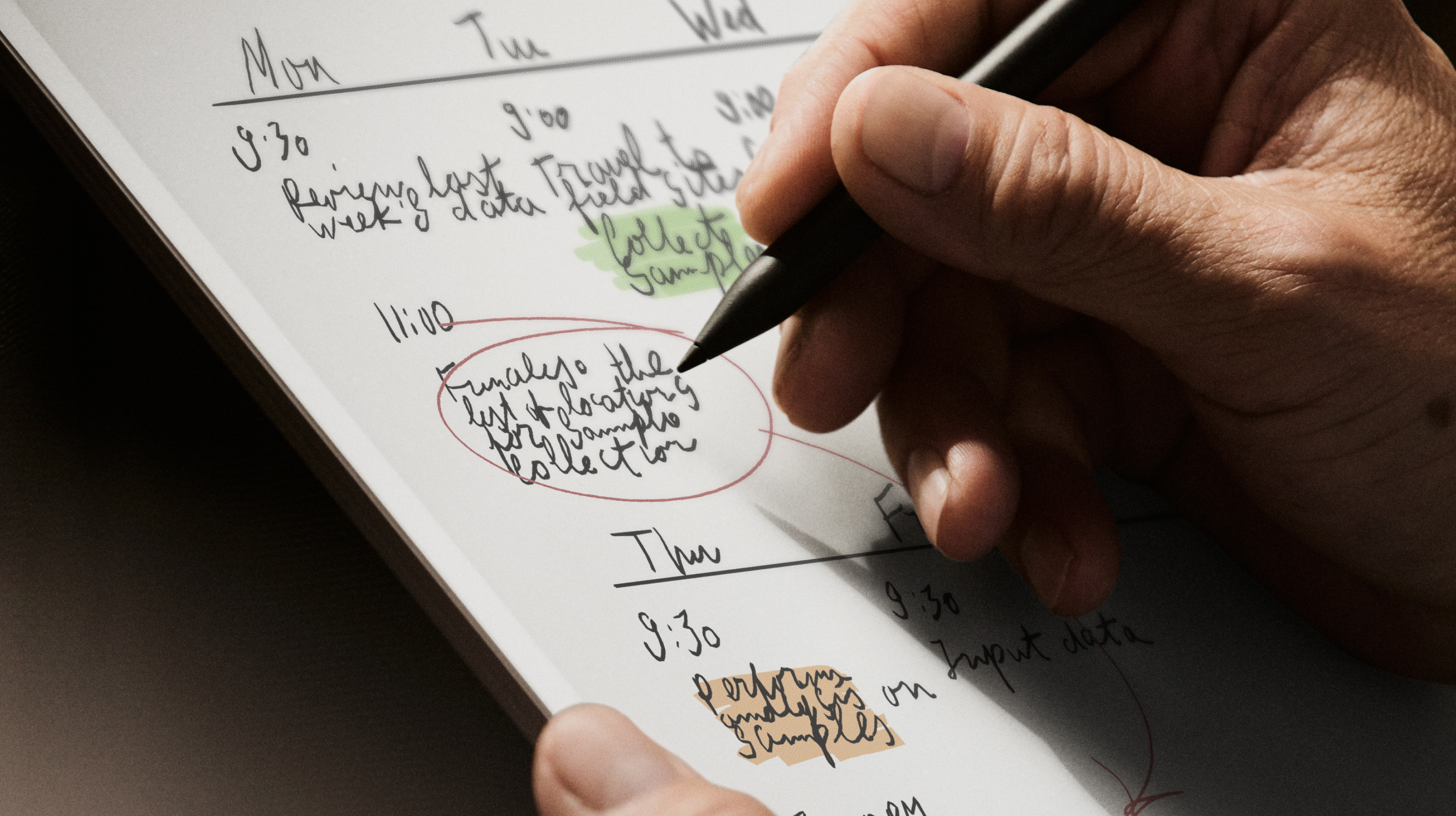 A hand writing a note on the reMarkable paper tablet with the Marker, planning the week.
