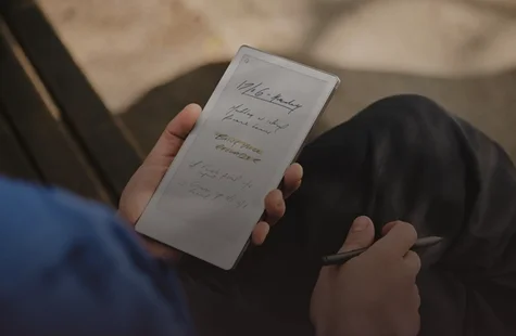 A person sitting with remarkable in his hands writing with a pen.