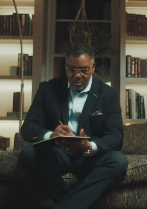 A man writing in a reMarkable paper tablet with the Marker while sitting on a couch.
