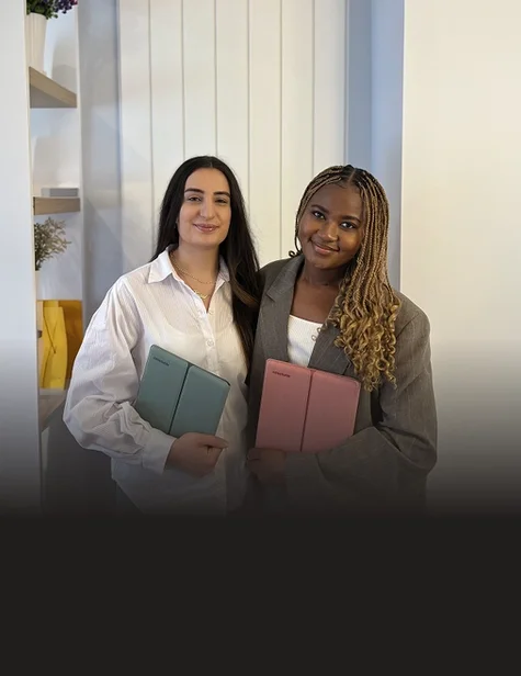 Dr. Lydie Kitenge holding a reMarkable Paper Pure tablet in a Mist Green sleeve folio, and Dr. Hazal Trench holding one in a Desert Pink sleeve folio.