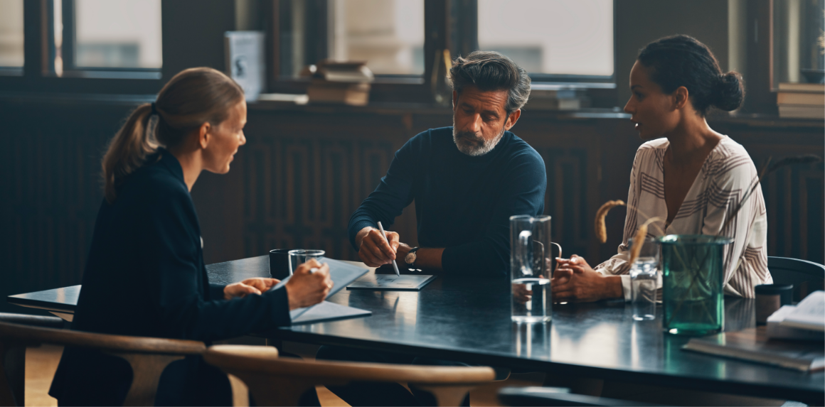 People in a meeting at a table without disrupting laptops.
