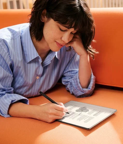 A woman lying on a sofa, deep in concentration working on a reMarkable Paper Pure