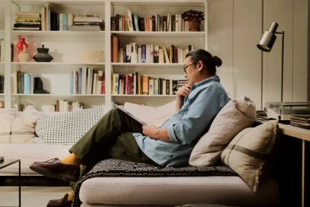 A man reading while relaxing on a sofa with a reMarkable paper tablet.