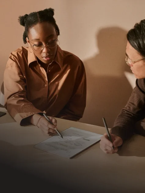Two people reviewing notes on a reMarkable paper tablet, writing with the Marker.