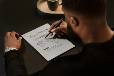 A man writing project milestones on a reMarkable paper tablet with the Marker.
