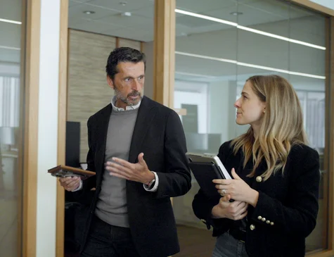 A reMarkable paper tablet in hand as colleagues walk through an office.
