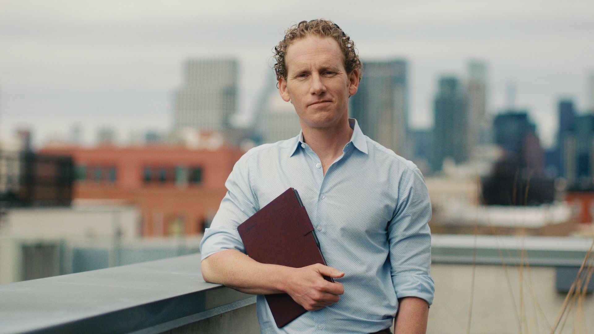 Jonah holding a reMarkable paper tablet with a city skyline in the background.