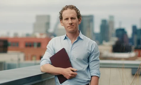 Jonah holding a reMarkable paper tablet with a city skyline in the background.