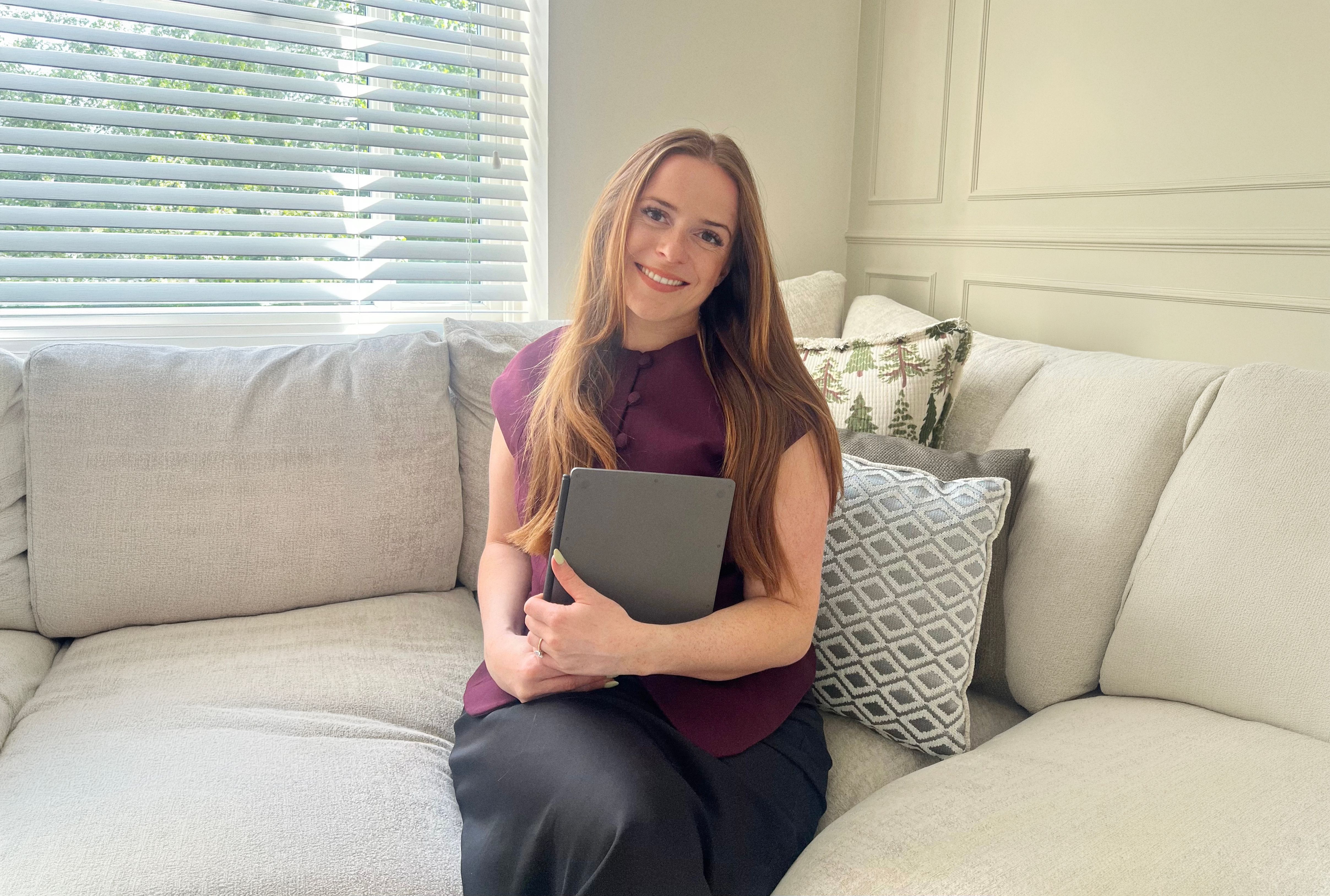 Mia Siddique sitting in her couch holding her reMarkable Paper Pure.