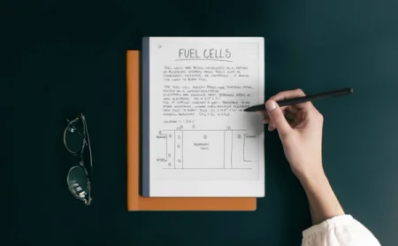 A reMarkable paper tablet displaying notes and a diagram, with a hand writing on the device with the Marker.