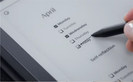 A reMarkable paper tablet displays a calendar with the Marker crossing out "Friday."
