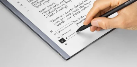 A reMarkable paper tablet displaying "Convert to text" with a hand navigating with the Marker.
