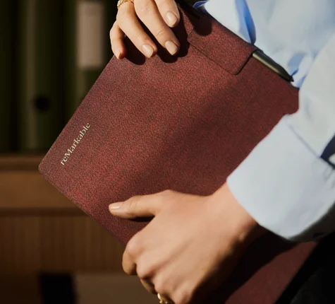 A man holding a reMarkable Paper Pro tablet with a burgundy Book Folio.