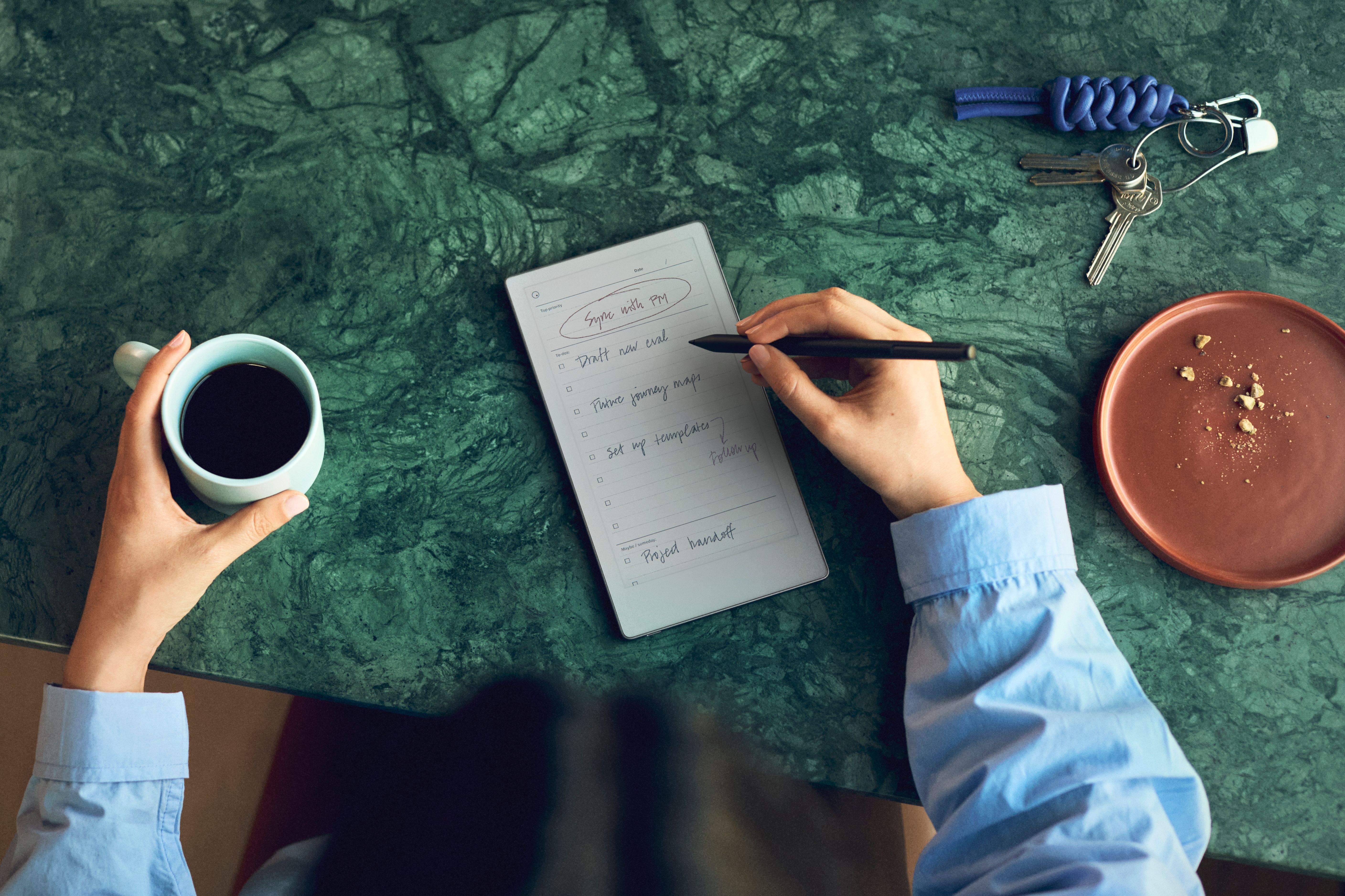 A professional taking notes on they reMarkable Paper Pro Move while drinking coffee.
