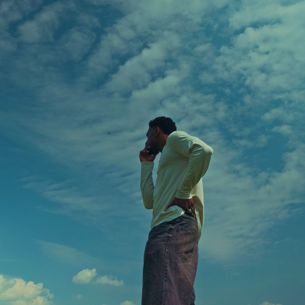 Jordan Jaiyeola standing outside thinking with a blue sky in the background