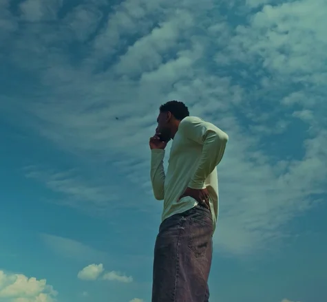 Jordan Jaiyeola standing outside thinking with a blue sky in the background