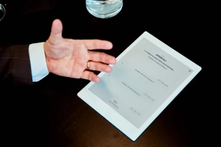 A hand next to a reMarkable paper tablet displaying an interview document.