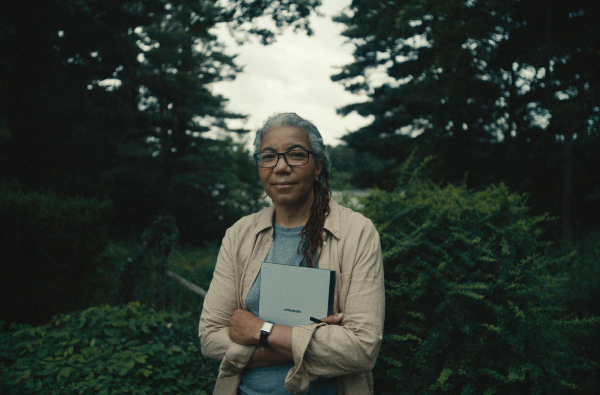 Woman standing with reMarkable paper tablet with trees in background