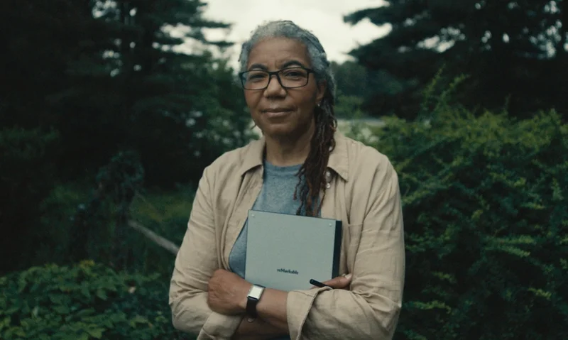 Woman standing with reMarkable paper tablet with trees in background