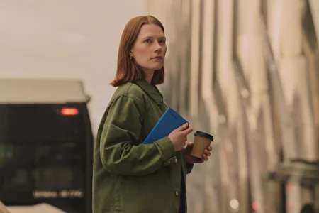 Woman in a green jacket holding a reMarkable Paper Pro Move with a Mosaic weave Book Folio in Cobalt.