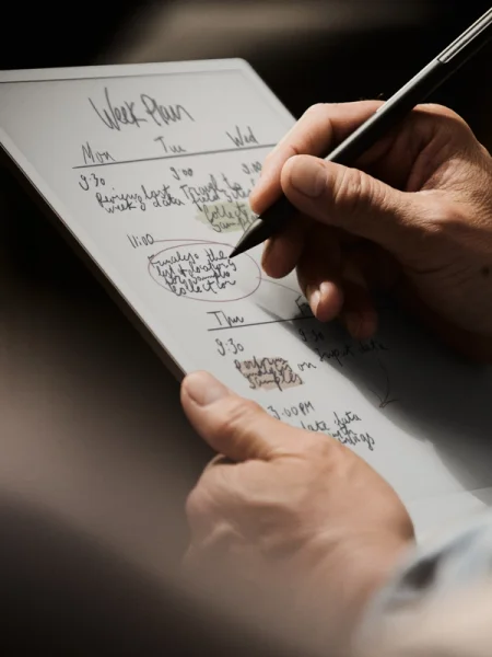 A reMarkable paper tablet showing a person writing a note with the Marker.