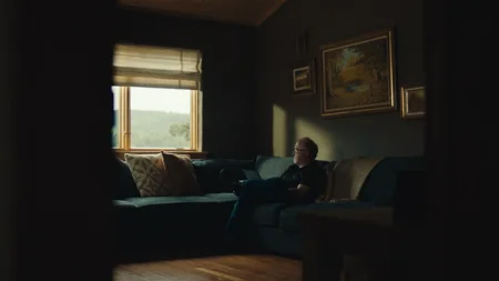 Phil with a reMarkable paper tablet on his lap sitting inside in a couch looking out the window.
