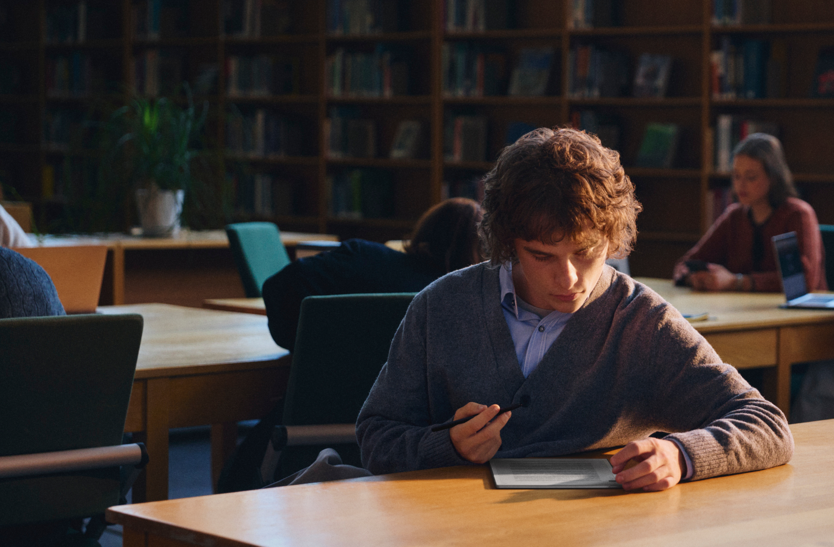 A student using a reMarkable Paper Pro tablet with the Marker in a library.