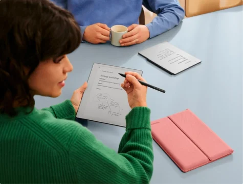 A woman in a meeting using a reMarkable paper tablet while sitting by a table.