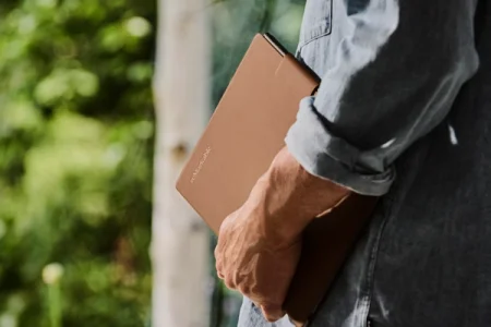 A reMarkable paper tablet being held by a person wearing a denim shirt.