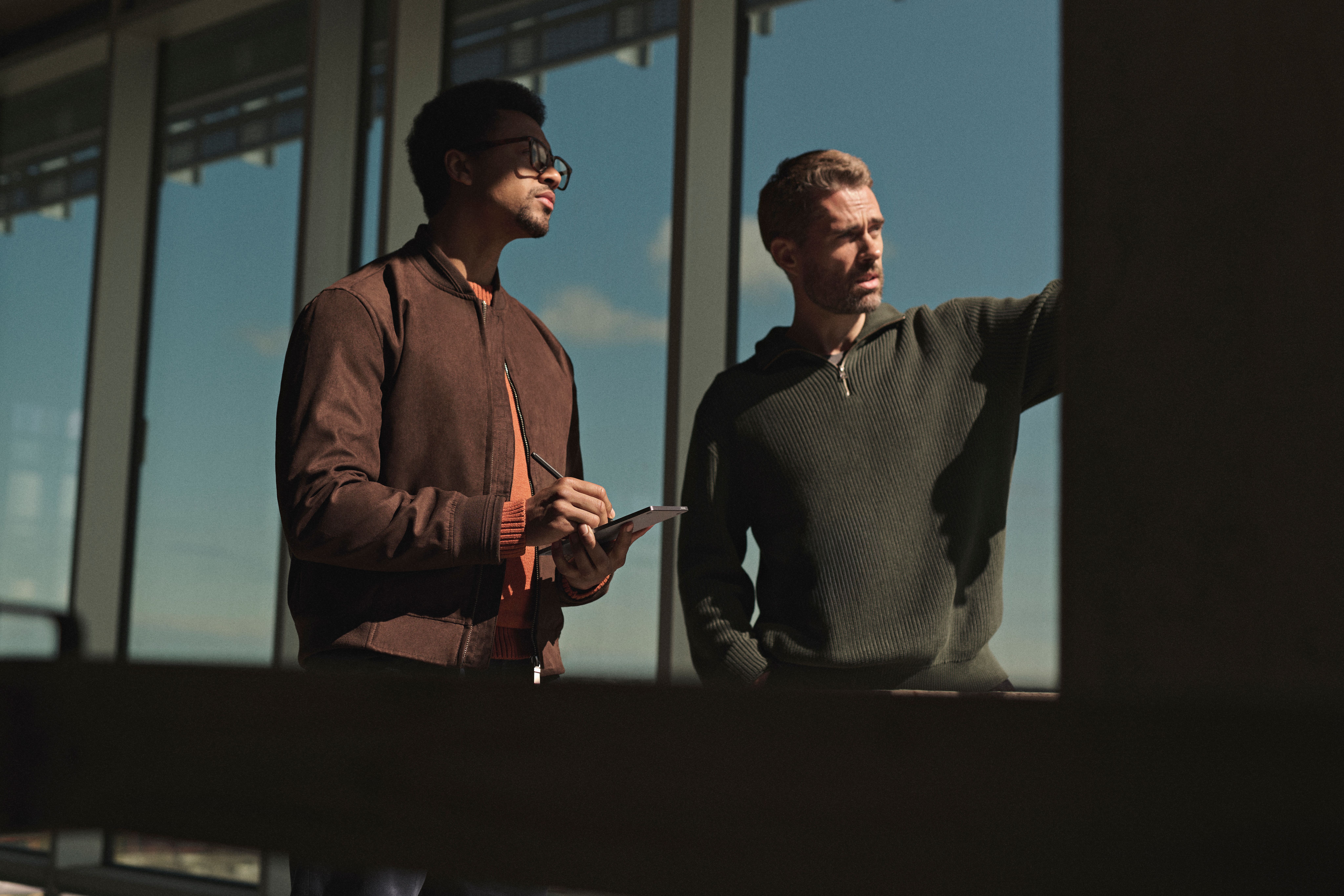Two men discussing design with a reMarkable Paper Pro Move tablet and Marker in hand on a building exterior.