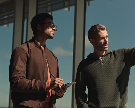 Two men discussing design with a reMarkable Paper Pro Move tablet and Marker in hand on a building exterior.