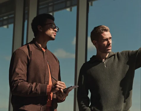 Two men discussing design with a reMarkable Paper Pro Move tablet and Marker in hand on a building exterior.