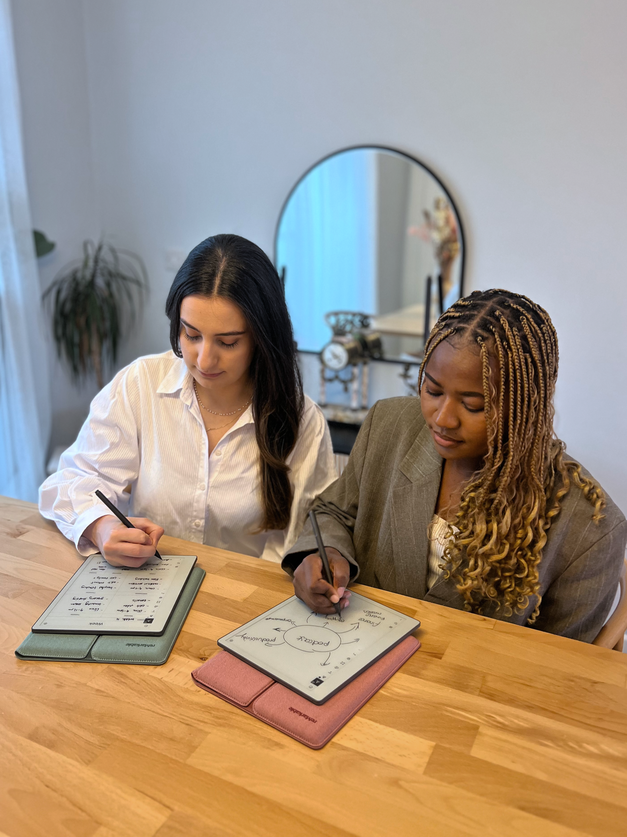 Hazal Trench and Lydie Kitenge sitting at a table, each writing on their own reMarkable Paper Pure tablet.