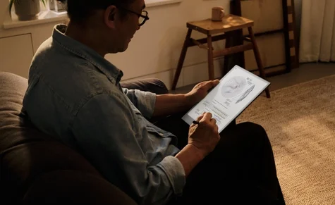 A person sitting with remarkable in his hands writing with a pen.