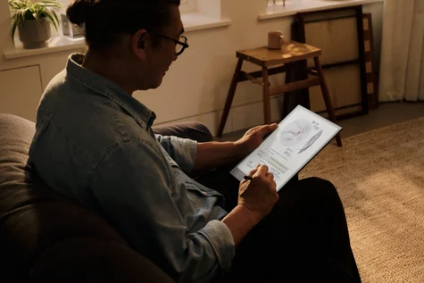 A person sitting with remarkable in his hands writing with a pen.