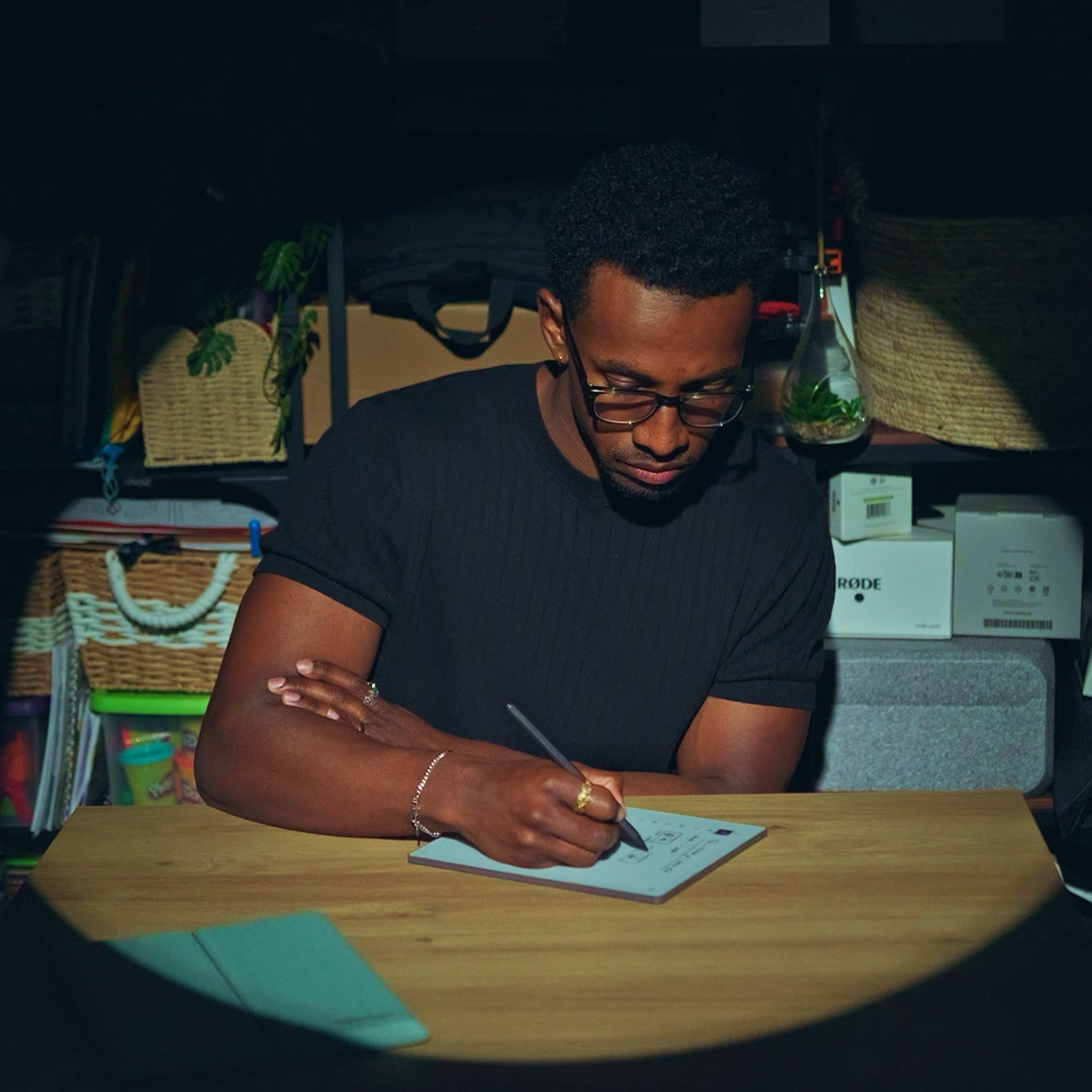 Jordan Jaiyeola sitting by his desk writing on his reMarkable Paper Pure tablet.