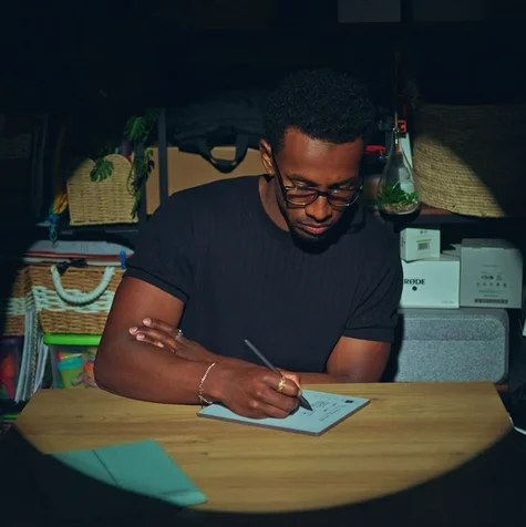Jordan Jaiyeola sitting by his desk writing on his reMarkable Paper Pure tablet.