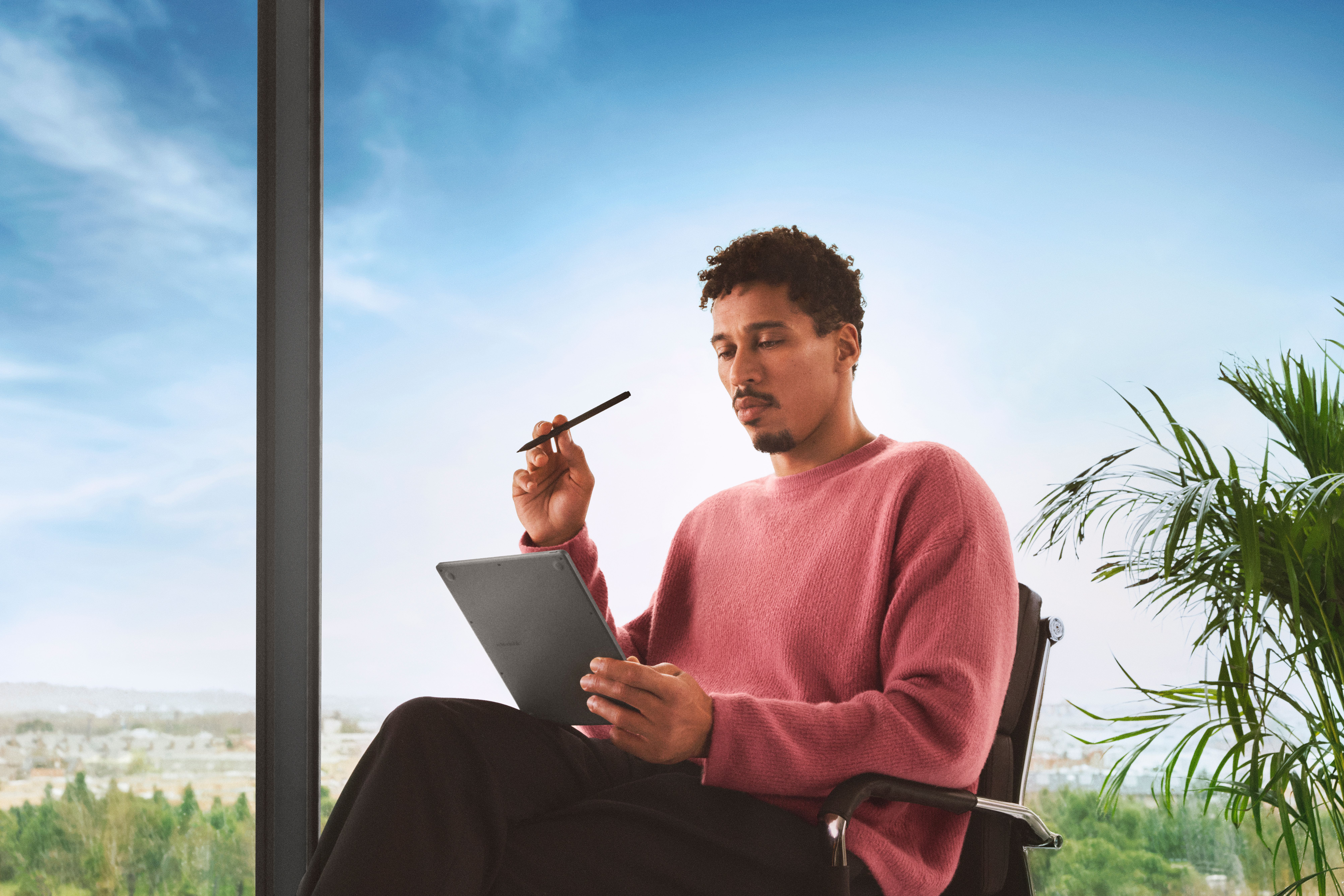 A man sitting in a chair, looking at reMarkable Paper Pure