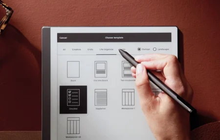 A reMarkable paper tablet showing template options and a hand selecting one with the Marker.