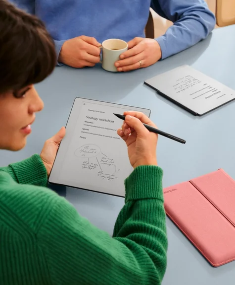 A woman and man in a meeting room sit in discussion while making notes on their reMarkable Paper Pure tablets