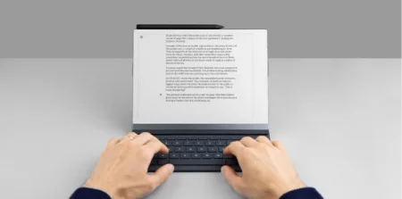 A reMarkable paper tablet with the Type Folio attached shows notes on the screen while a person types.