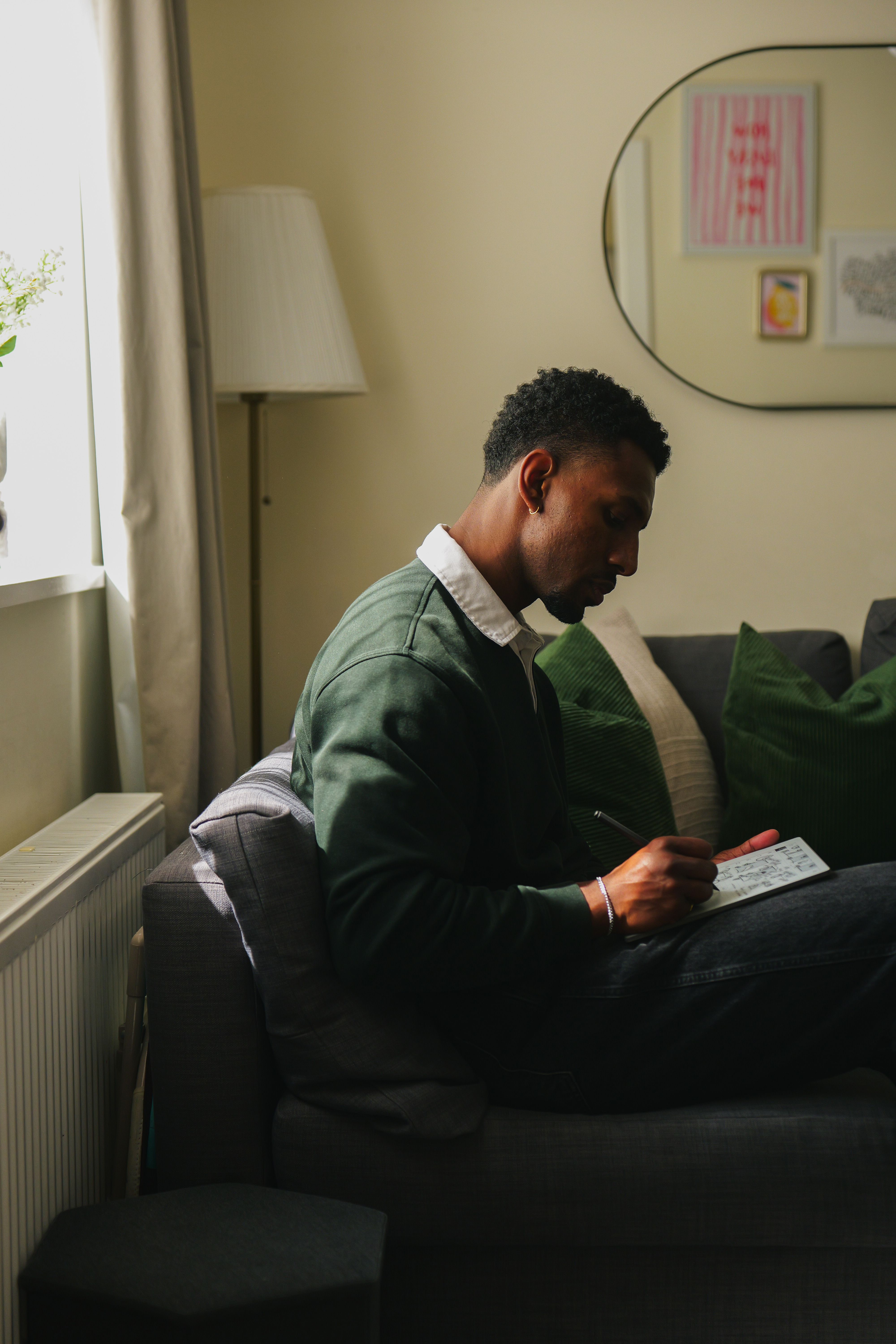 Jordan Jaiyeola sitting on his couch while writing on his reMarkable Paper Pure tablet.