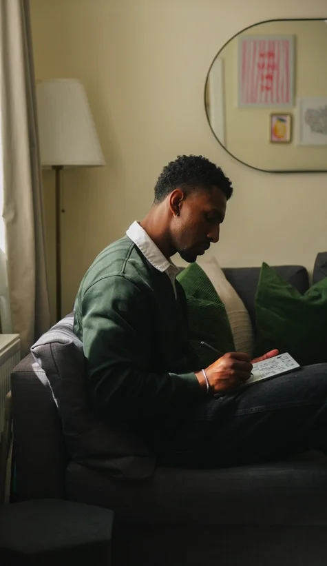 Jordan Jaiyeola sitting on his couch while writing on his reMarkable Paper Pure tablet.