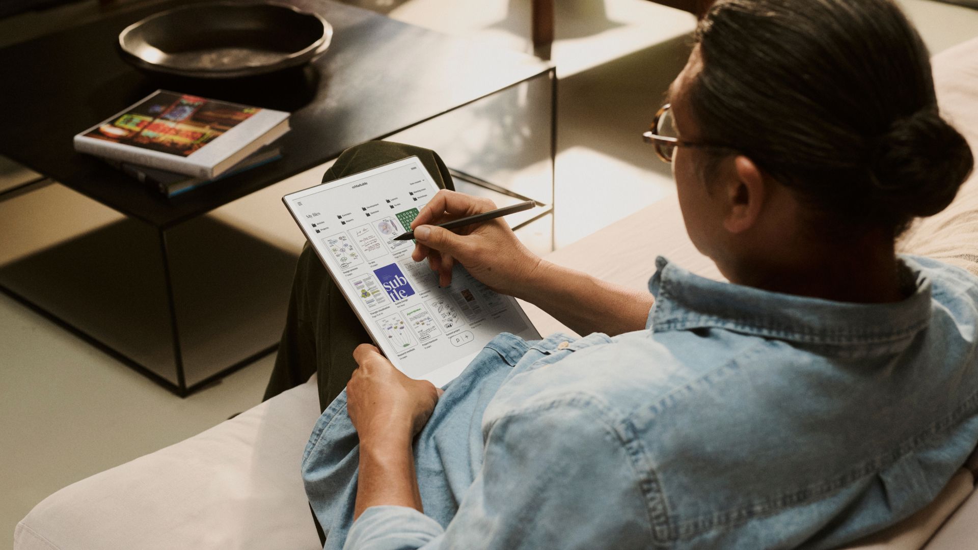 A person in a couch using a reMarkable paper tablet to write with Marker Plus.
