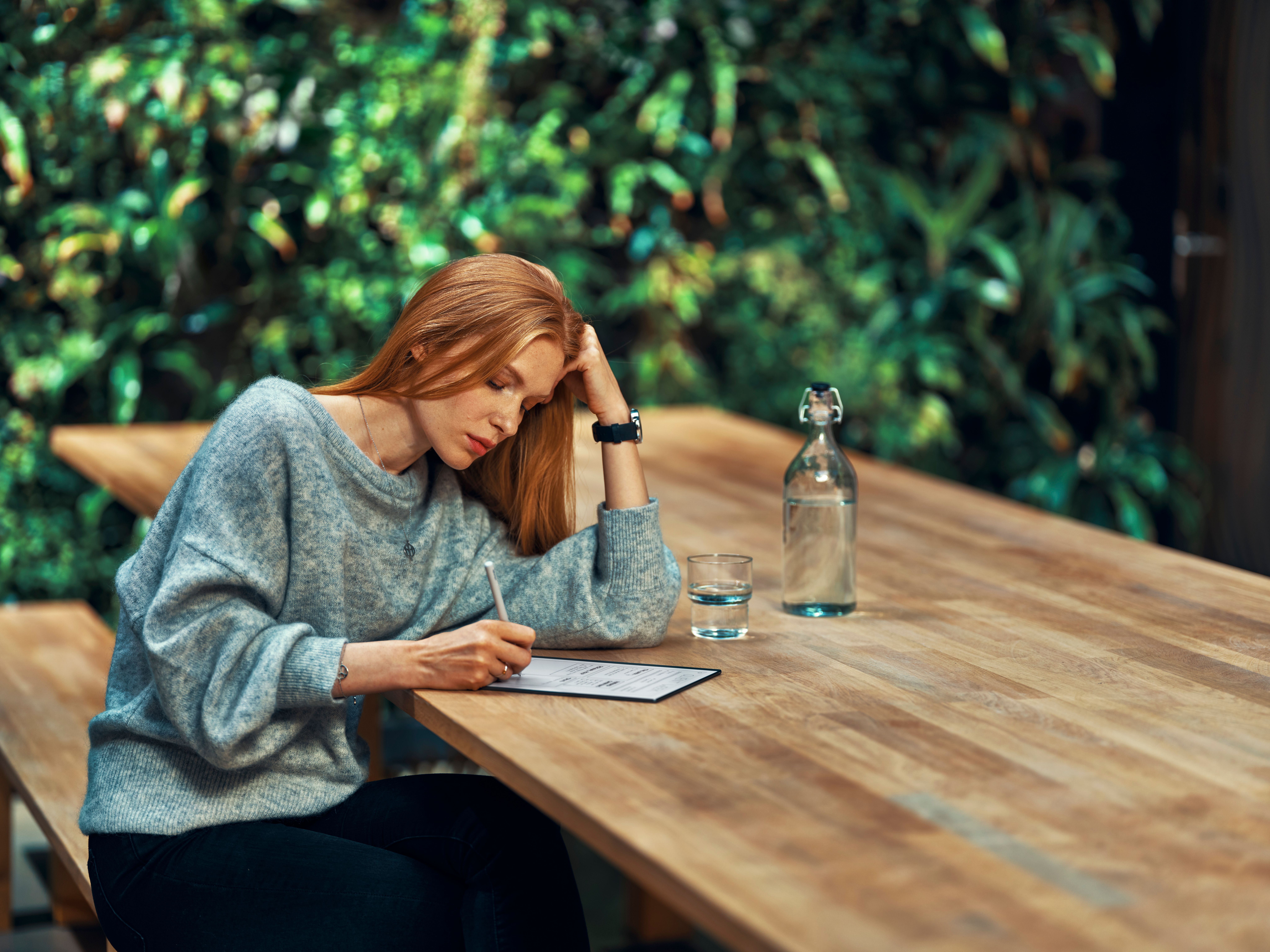 A person in deep focus writing on a reMarkable paper tablet